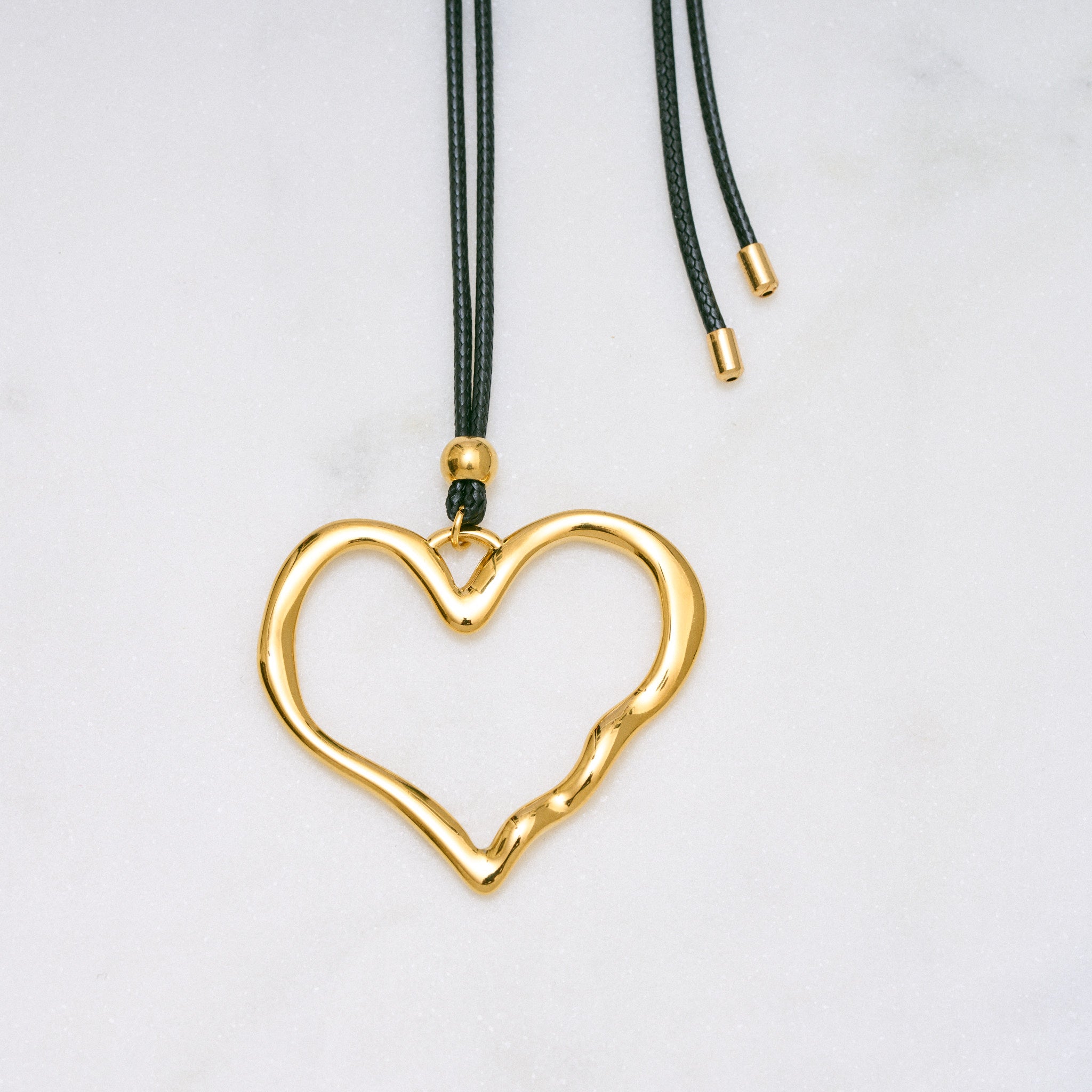 Trendige goldene Herzkette mit Schnurband und dem Schriftzug ‚LOVE‘. Der 90er-Jahre-inspirierte Schmuck bietet eine verspielte und kraftvolle Note, mit flexibler Verschlussmöglichkeit durch Knoten oder Schlaufe.
