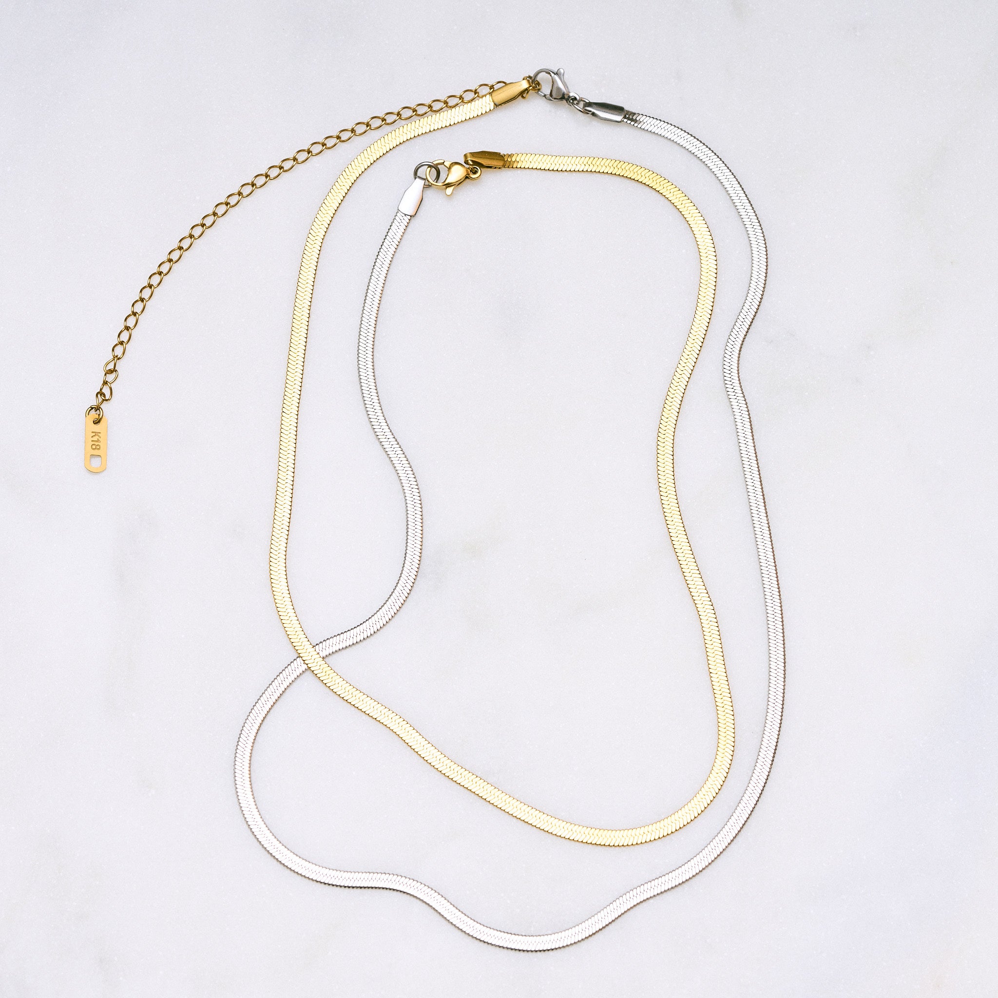 Zwei Snake Mini Ketten in Silber und Gold miteinander verbunden, die sich wie eine zarte Schlange um den Hals legen und im Licht glitzern. Die Bi-Color-Kombination betont den Trend-Look.
