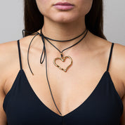 Trendige goldene Herzkette mit Schnurband und dem Schriftzug ‚LOVE‘. Der 90er-Jahre-inspirierte Schmuck bietet eine verspielte und kraftvolle Note, mit flexibler Verschlussmöglichkeit durch Knoten oder Schlaufe.
