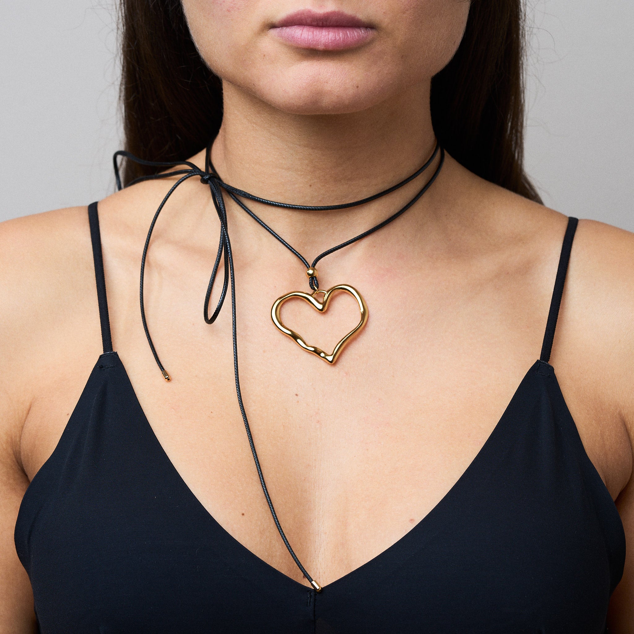 Trendige goldene Herzkette mit Schnurband und dem Schriftzug ‚LOVE‘. Der 90er-Jahre-inspirierte Schmuck bietet eine verspielte und kraftvolle Note, mit flexibler Verschlussmöglichkeit durch Knoten oder Schlaufe.