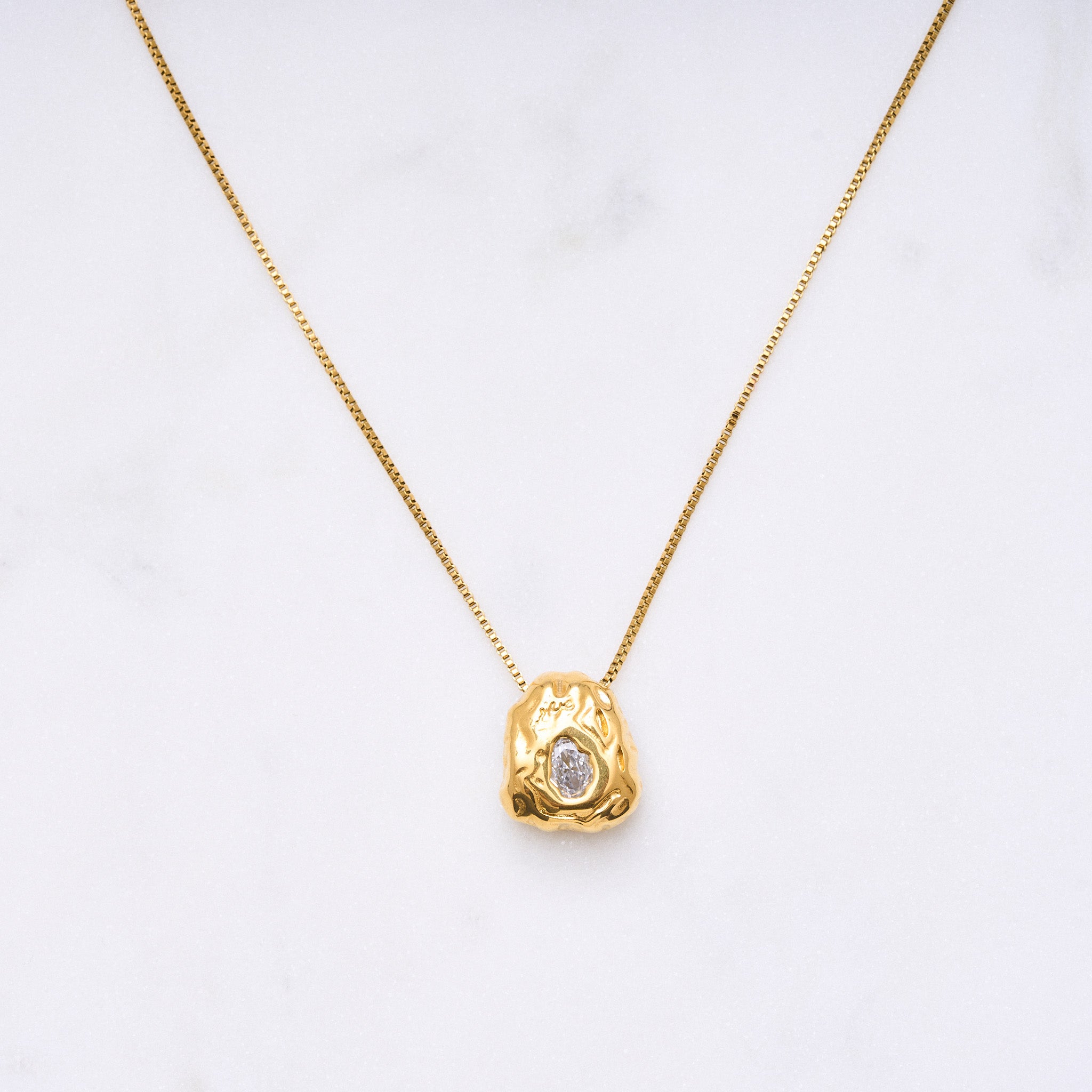 Ein Blickfang: Eine Kette mit einem organischen Anhänger, der mit einem funkelnden Zirkonia in der Mitte verziert ist. Der Anhänger symbolisiert die Schätze in den Bergen und erinnert daran, dass jeder seinen eigenen inneren Schatz hat. Die Kette ist ein Statement-Schmuckstück, das alleine für Aufmerksamkeit sorgt und in Kombination mit anderen Accessoires noch mehr Strahlkraft entfaltet.