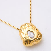 Ein Blickfang: Eine Kette mit einem organischen Anhänger, der mit einem funkelnden Zirkonia in der Mitte verziert ist. Der Anhänger symbolisiert die Schätze in den Bergen und erinnert daran, dass jeder seinen eigenen inneren Schatz hat. Die Kette ist ein Statement-Schmuckstück, das alleine für Aufmerksamkeit sorgt und in Kombination mit anderen Accessoires noch mehr Strahlkraft entfaltet.