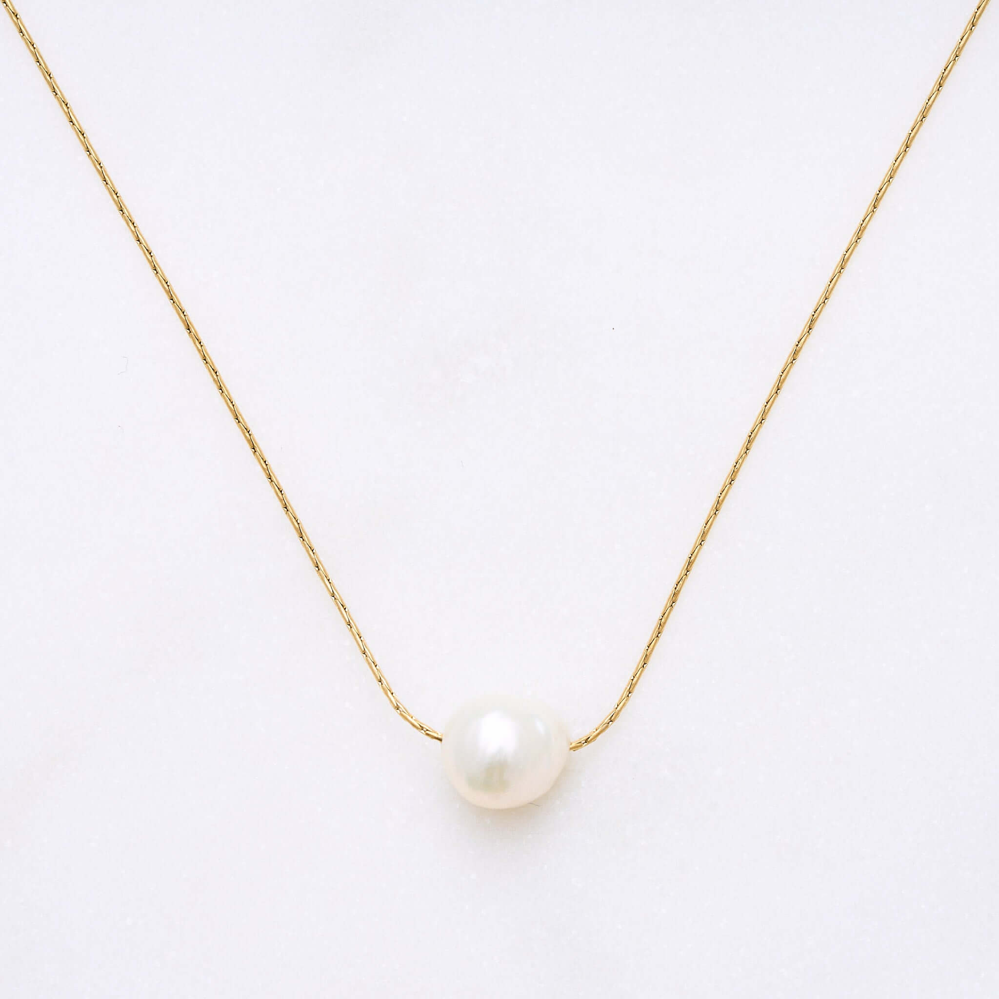 Bild einer eleganten Pearly-Halskette mit einer mittelgroßen Süßwasserperle. Jede Perle hat eine einzigartige Form, was jede Kette zu einem Unikat macht. Die Kette kann alleine oder in Kombination mit anderen Ketten getragen werden, passend für Strand- oder City-Looks.